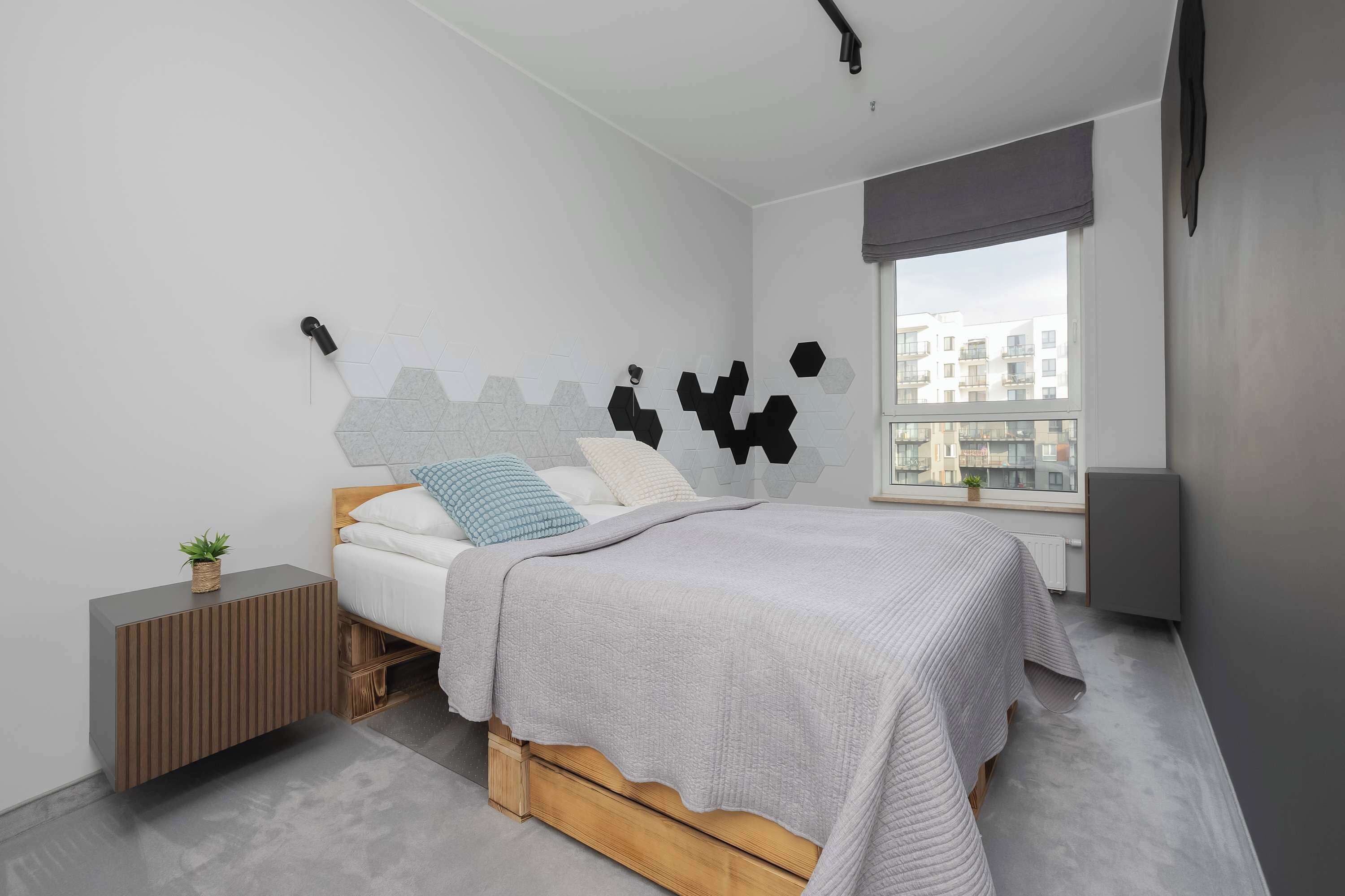 A modern bedroom with a bed, a bedside table, a window, and a city view.