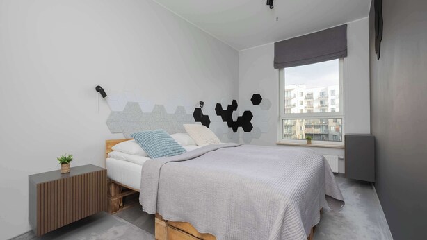 Une chambre moderne avec un lit, une table de chevet, une fenêtre et une vue sur la ville.