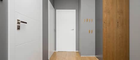 A hallway with a wooden floor, white walls, and a wooden wardrobe.