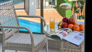 A wicker chair, a glass of juice, and a fruit bowl with apples and oranges on a table. - Qoople Elite 2 City B1 - Cozy 1-bedroom apartment in Alanya (Alanya)