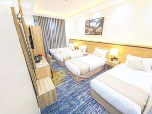 Een hotelkamer met twee bedden, een houten nachtkastje, een bureau en een aan de muur bevestigde televisie.