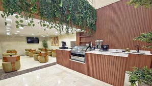 A reception area with a wooden counter, seating, and a television. - Romance AlBadr Hotel (Makkah)