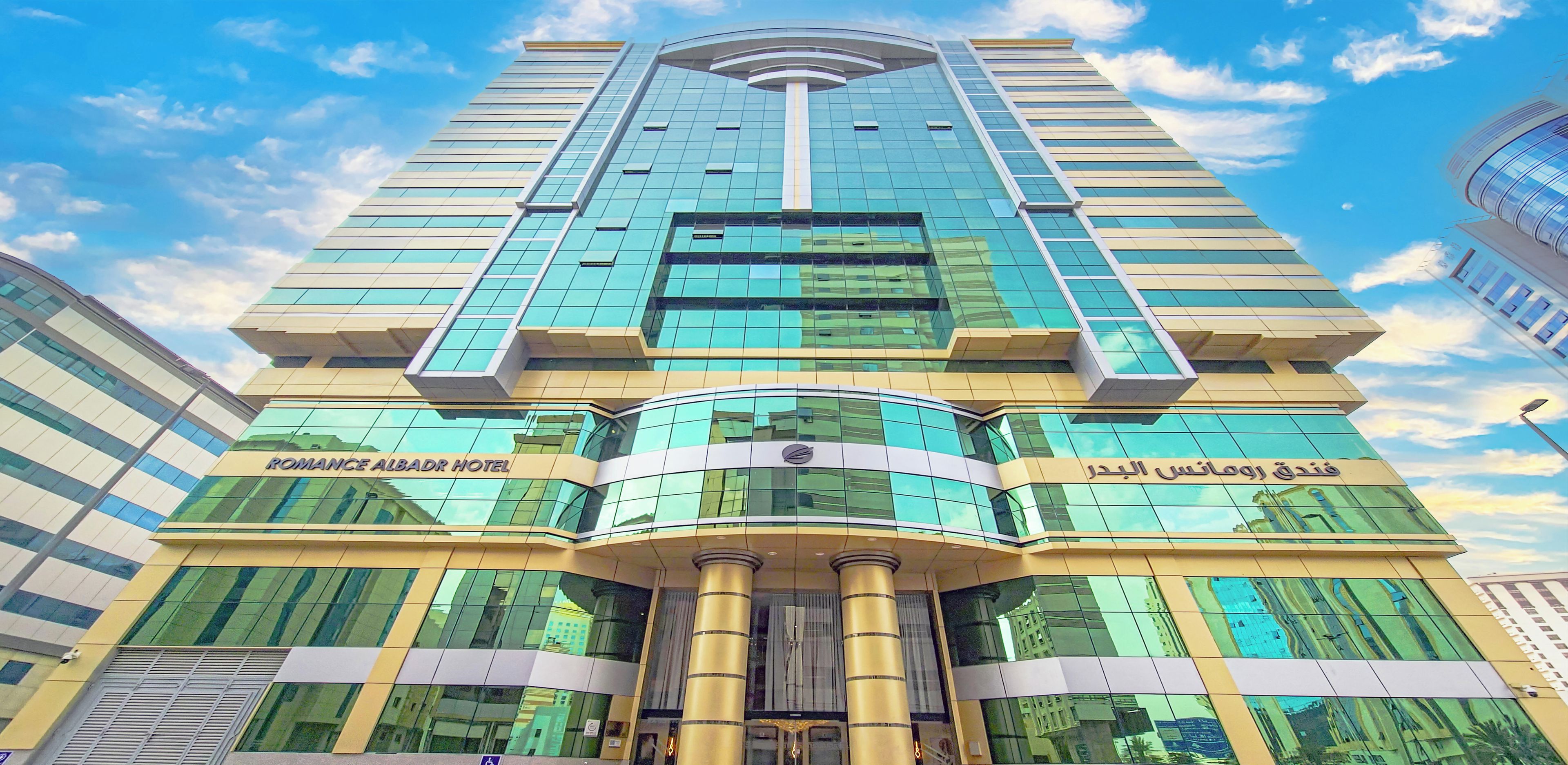 A modern hotel with a curved facade, large glass windows, and a prominent entrance with a golden column.
