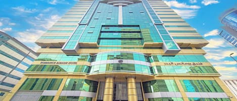 A modern hotel with a curved facade, large glass windows, and a prominent entrance with a golden column.