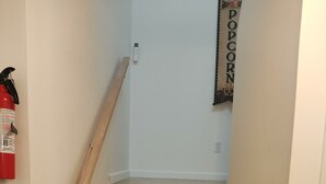 Una escalera de madera con barandilla, un extintor y un enchufe en la pared.