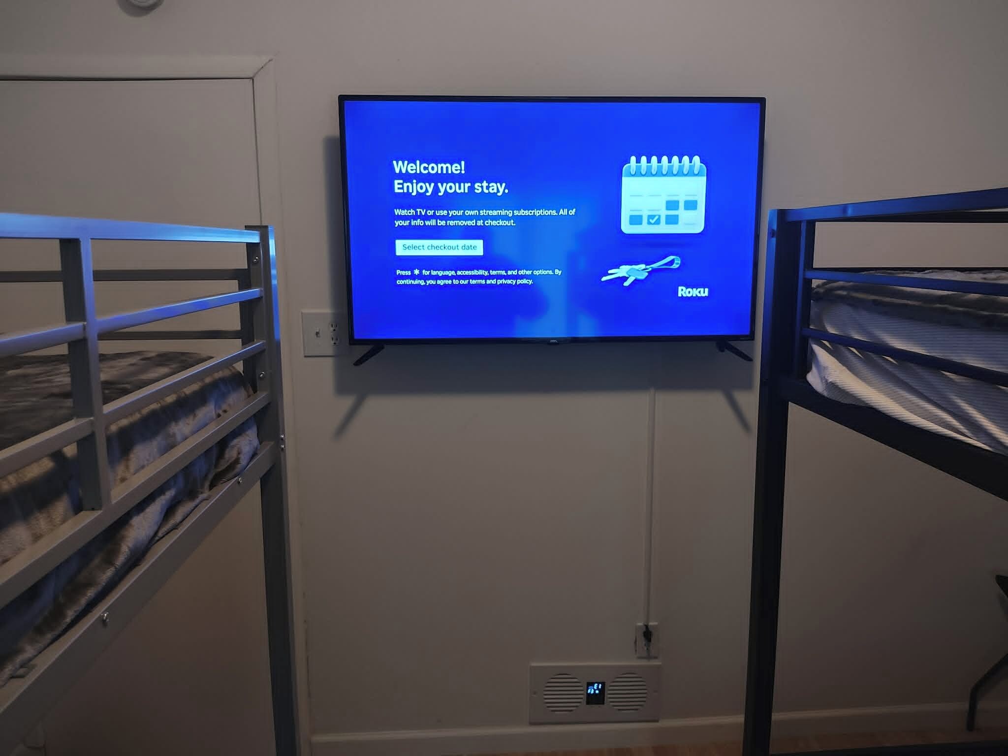 Un televisor fijado en la pared mostrando un mensaje de bienvenida y opciones para el registro de salida.