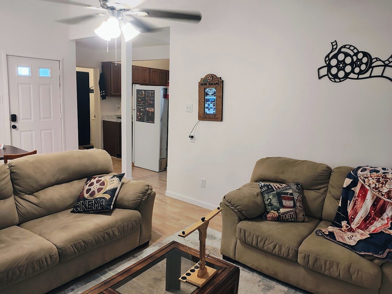 Una sala de estar con dos sofás color beige, una mesa de centro y un ventilador de techo.