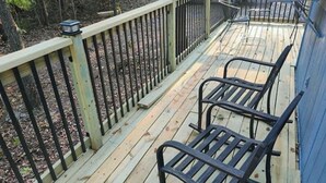 Una terraza de madera con barandillas metálicas y dos mecedoras.