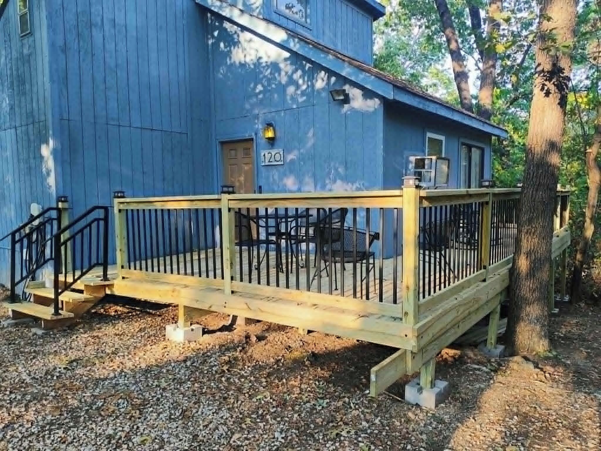 A blue building with a wooden deck and a metal railing.