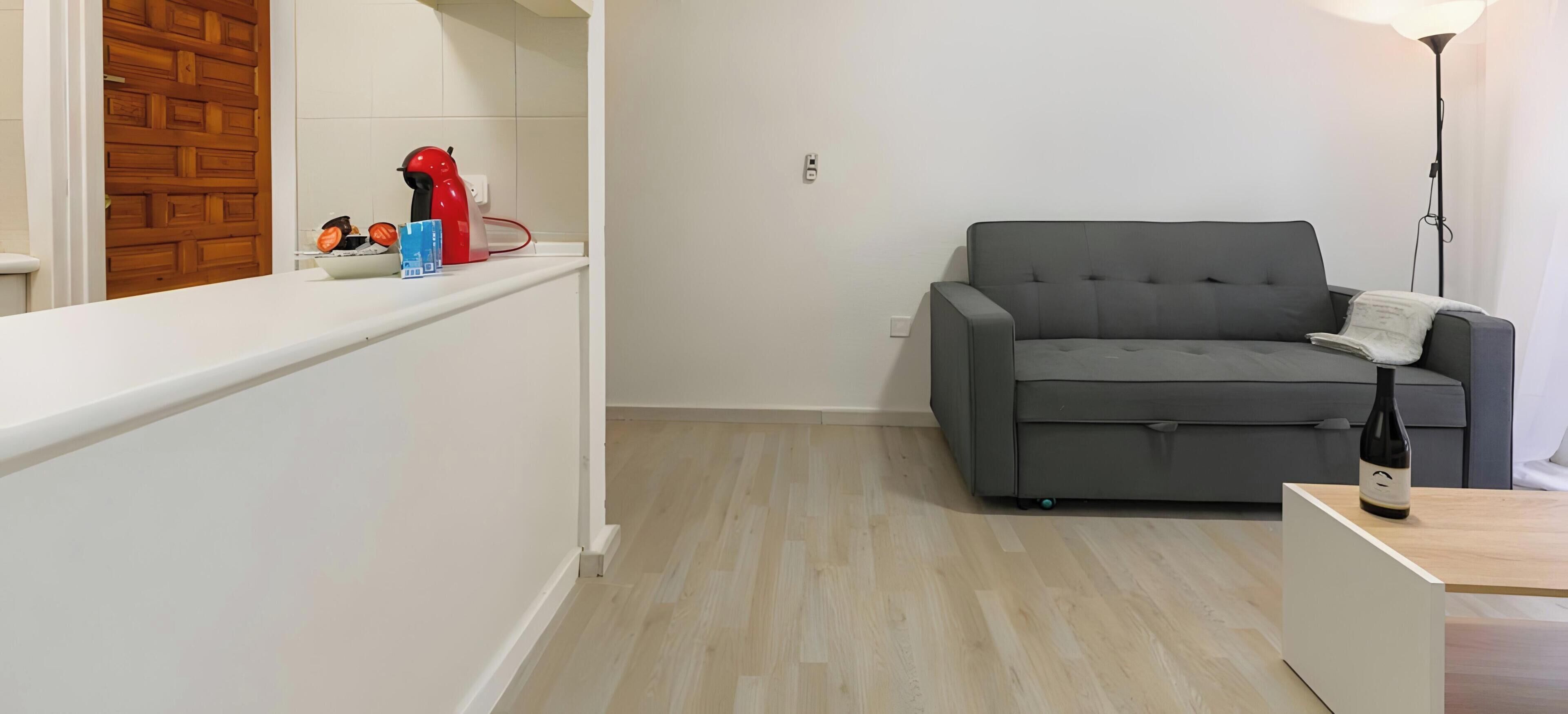 Ein modernes Wohnzimmer mit grauem Sofa, einem weißen Couchtisch und einer Stehlampe.