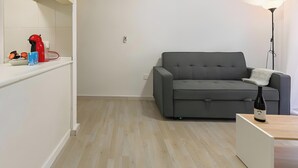 Ett modernt vardagsrum med en grå soffa, ett vitt soffbord och en golvlampa.