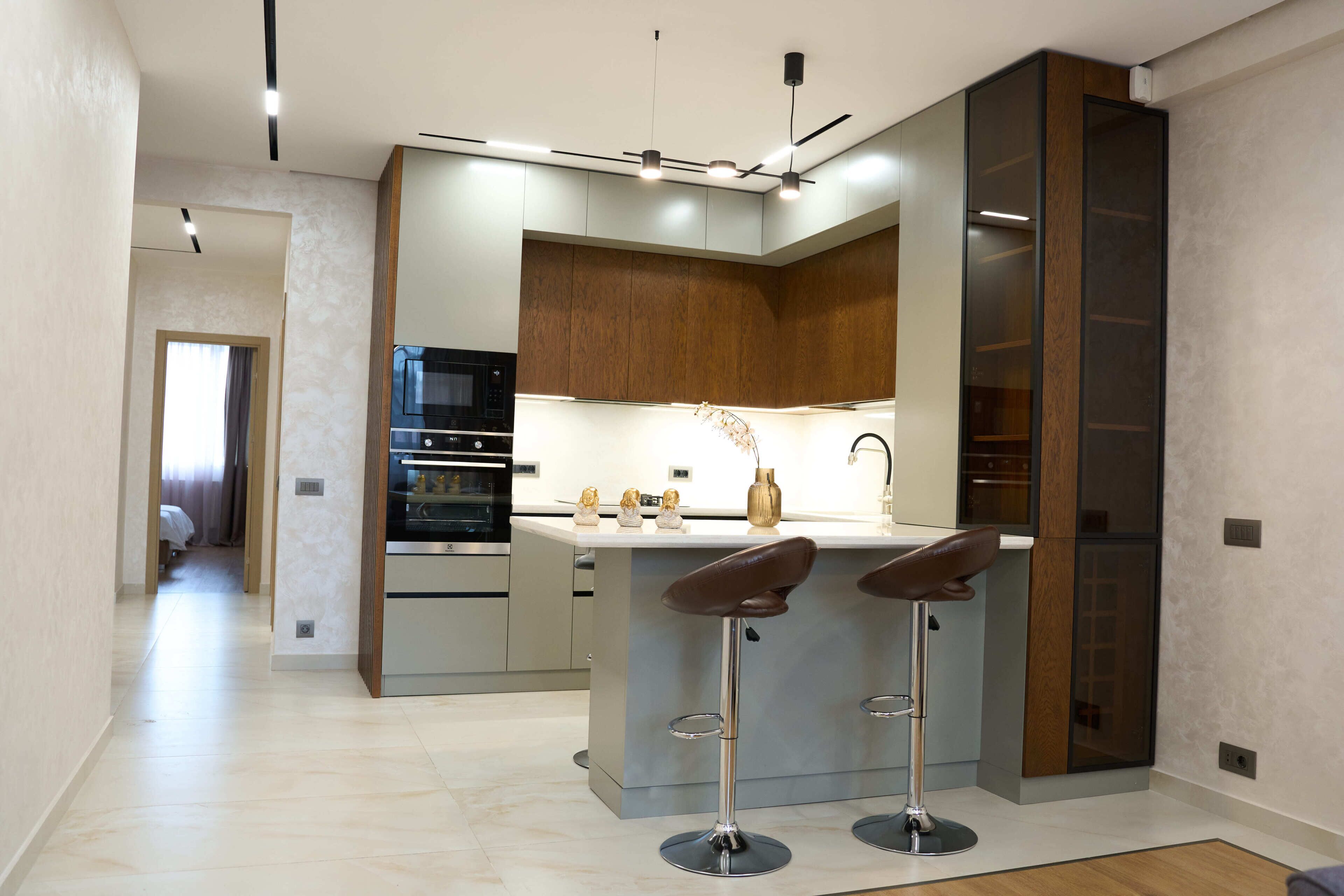 Uma cozinha moderna com uma ilha central, banquetas e eletrodomésticos embutidos.