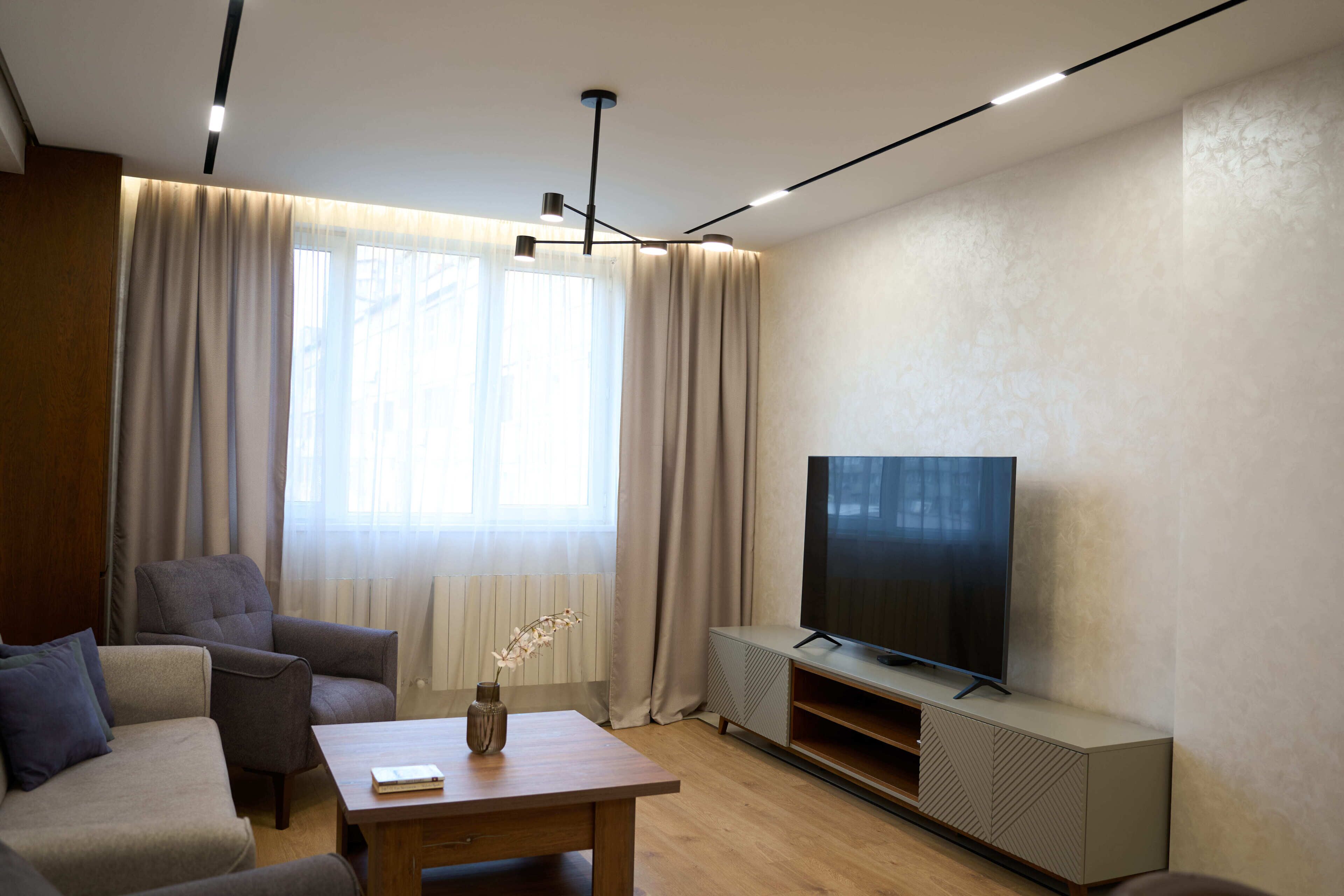 A modern living room with a sofa, a coffee table, a TV, and a radiator.
