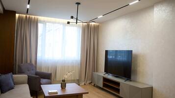 A modern living room with a sofa, a coffee table, a TV, and a radiator.