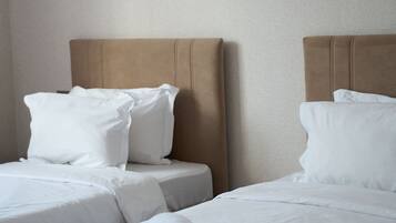 A hotel room with two beds, each with white linens and pillows, and a headboard.