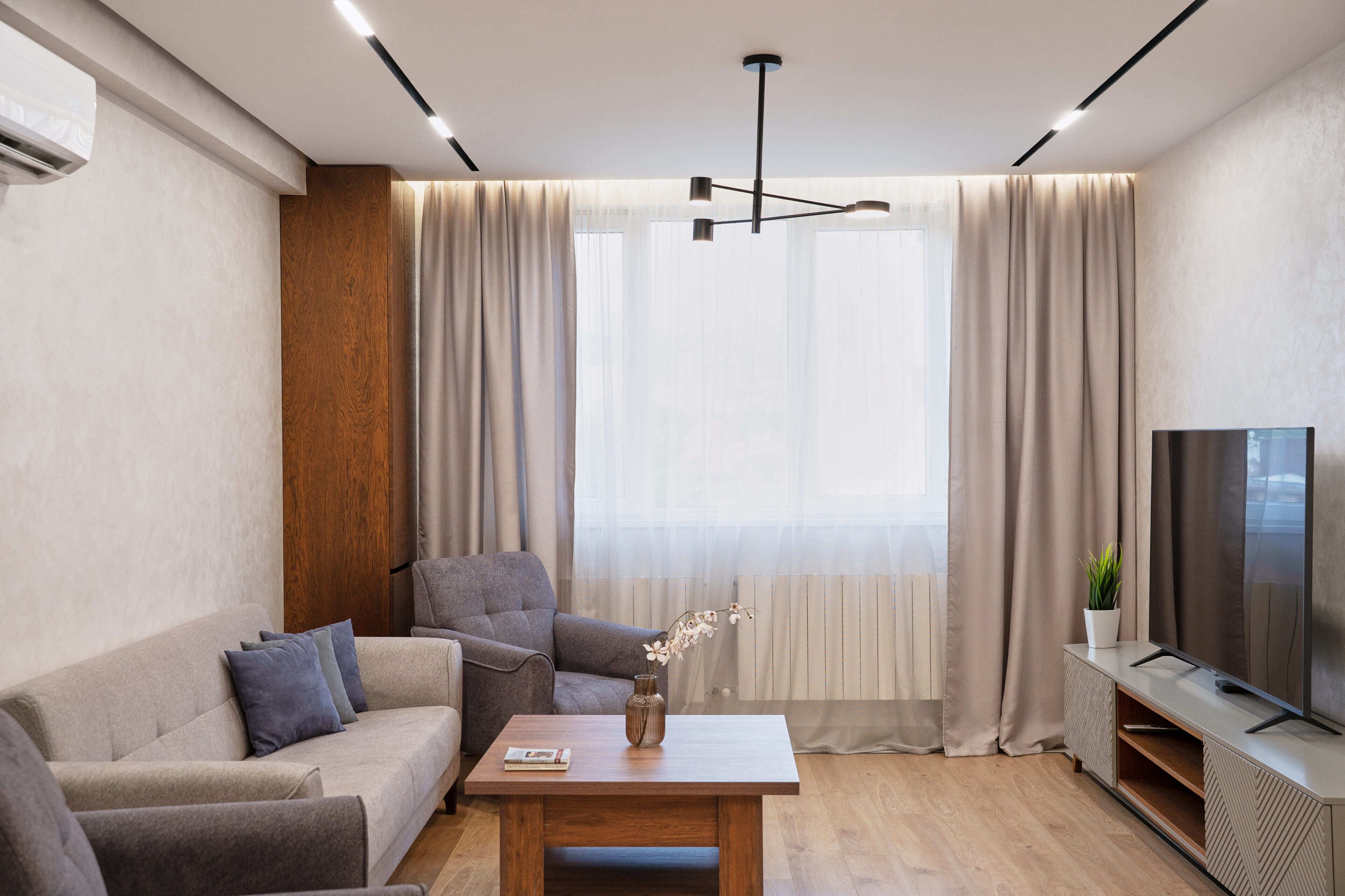 Una sala moderna con un sofá, una mesa de centro y un televisor sobre un mueble.