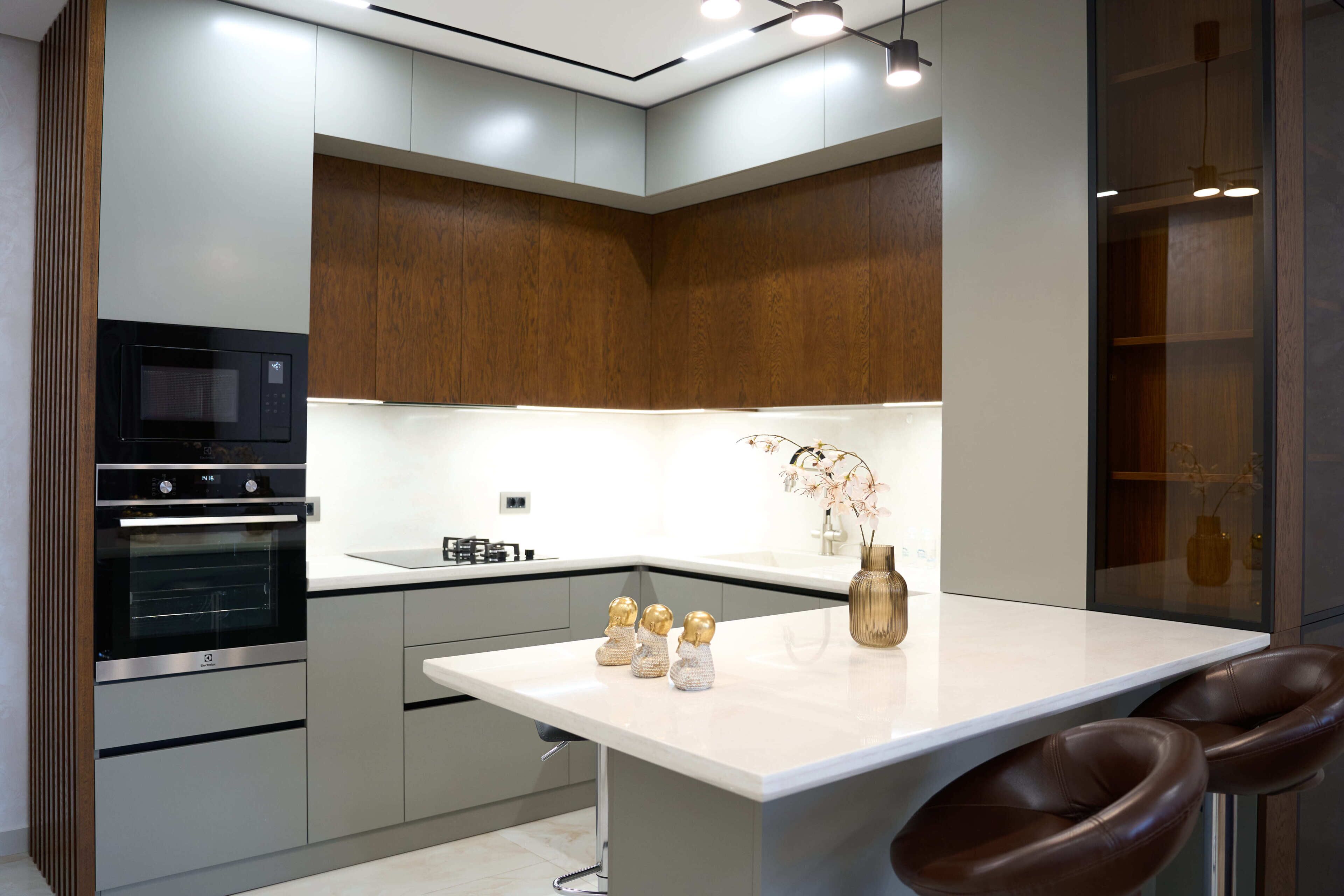 A modern kitchen with built-in appliances, a white countertop, and a wooden accent wall.