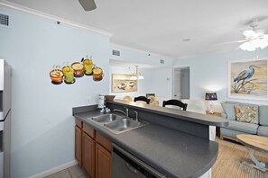 A kitchen with a built-in dishwasher, a double sink, and a dining area with a table and chairs.