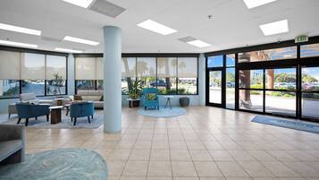 A spacious lobby with a large column, seating area, and large windows offering a view of the parking lot.