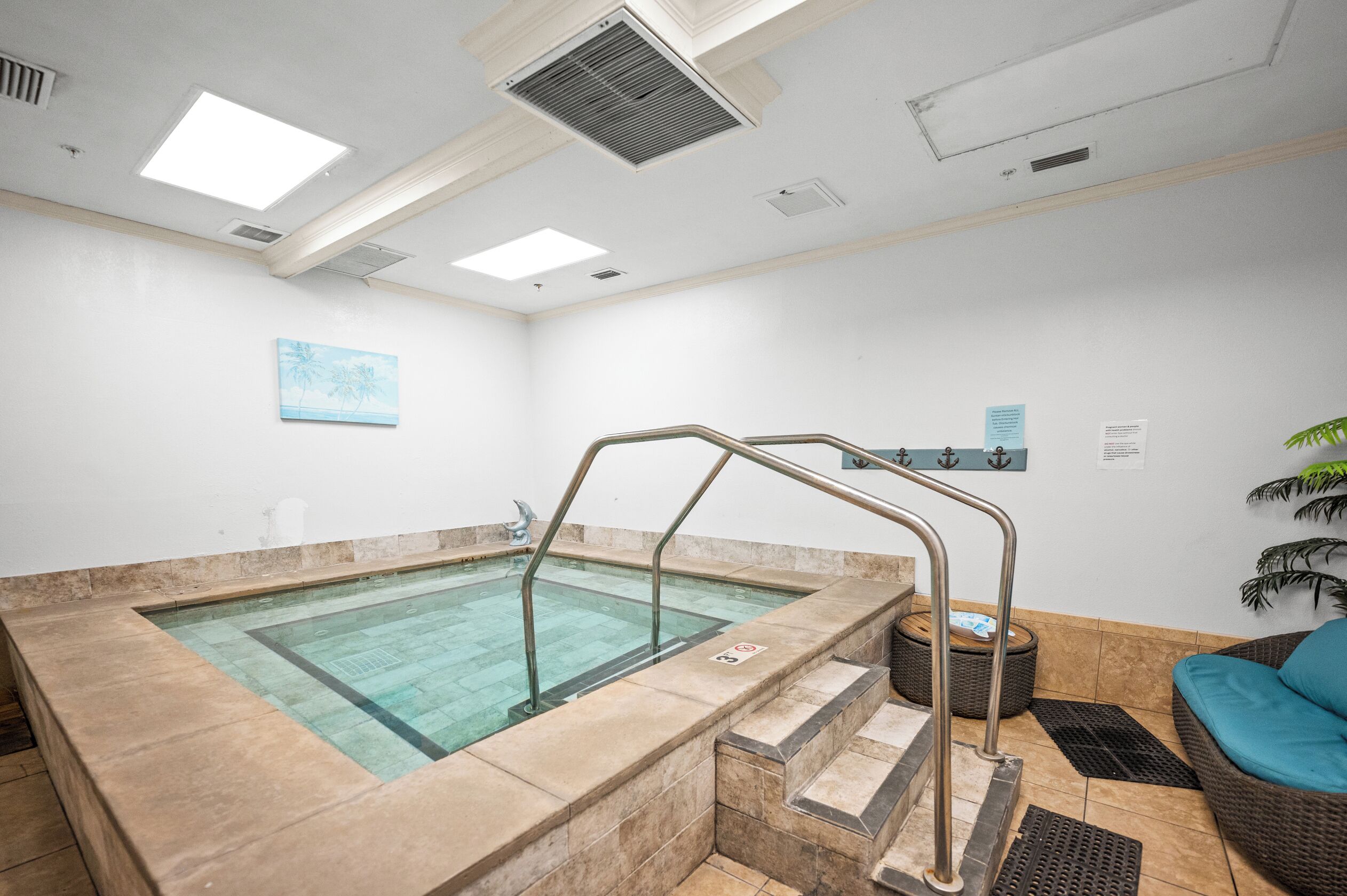 A spa area with a hot tub, a staircase, and a wicker sofa.