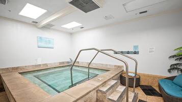 A spa area with a hot tub, a staircase, and a wicker sofa.