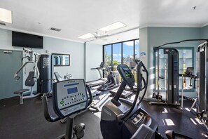 A gym with various exercise equipment, including treadmills and weight machines, and large windows offering a view of the outside. - Remodeled 2BR Condo | Beach Access & Pools | Penthouse Gulf Views (Gulf Shores)