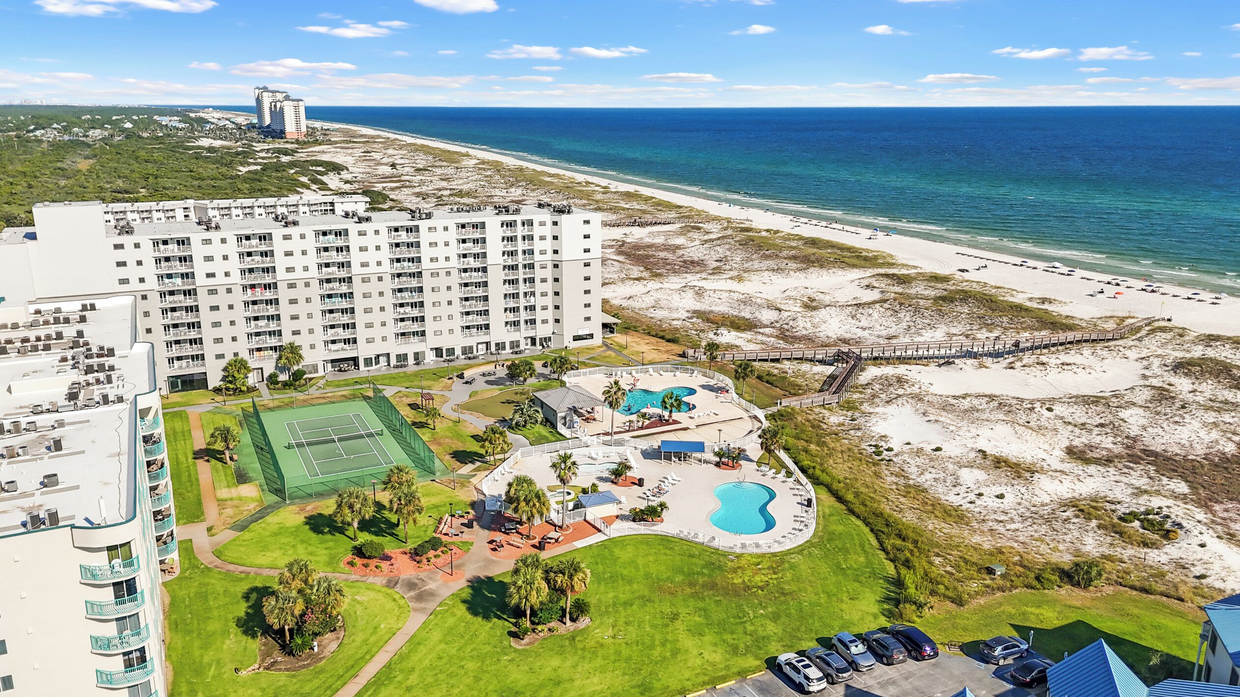 A resort with a large building, a beach, and a pool area.