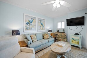 A living room with a sofa, a coffee table, a TV, and artwork on the wall.