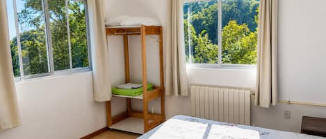 A room with a bunk bed, a radiator, and a window with curtains.