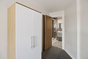 A hallway leading to a bathroom with a shower and a toilet visible. - Modern 2 Bedroom Flat l Manchester city l Sleeps 5 ! (Manchester)