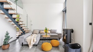 En moderne stue med en grå sofa, et rundt bord og en pejs.