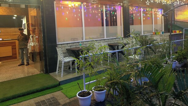 An outdoor seating area with tables and chairs, surrounded by potted plants. - Hotel New Empire (Gangtok)