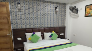 A hotel room with a patterned wall, a bed with a striped bedspread, and a wooden door. - Hotel New Empire (Gangtok)