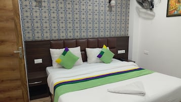A hotel room with a patterned wall, a bed with a striped bedspread, and a wooden door.