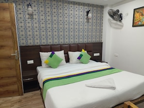 Ett hotellrum med en vägg som har ett mönster, en säng med ett randigt överkast och en dörr av trä.
