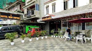 A hotel named 'Hotel New Empire' with a paved outdoor area, potted plants, and outdoor seating. - Hotel New Empire (Gangtok)