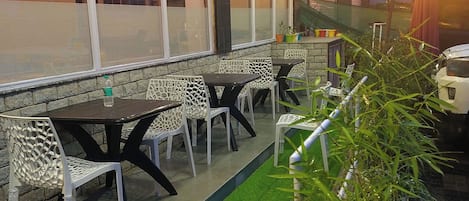 An outdoor seating area with tables and chairs, string lights, and potted plants.