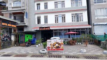 A hotel named 'Hotel New Empire' with a signboard, outdoor seating area, and a parked car.