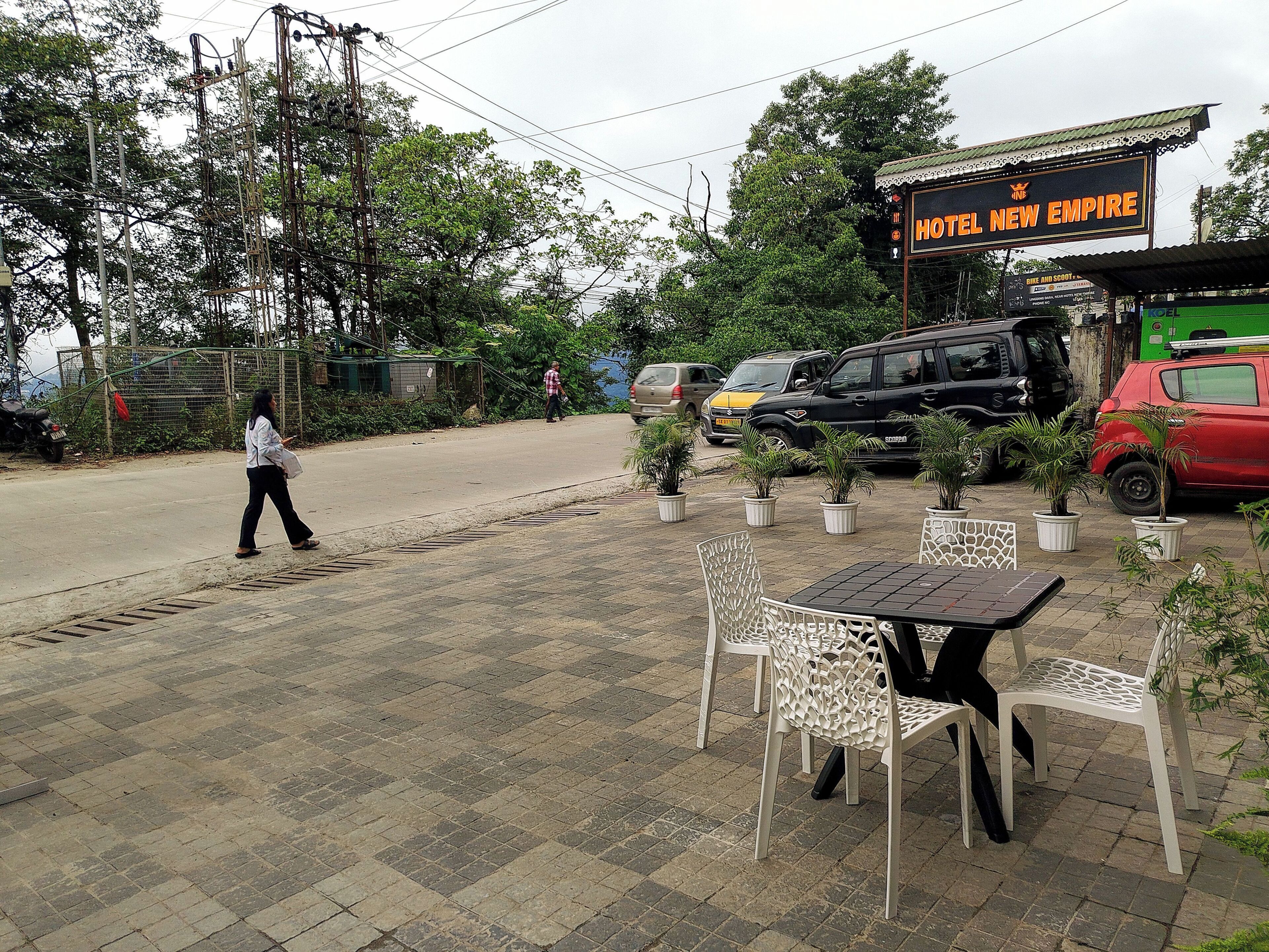 A hotel named 'Hotel New Empire' with outdoor seating and potted plants.