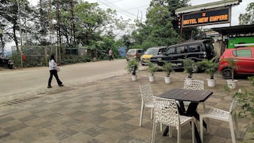 A hotel named 'Hotel New Empire' with outdoor seating and potted plants.