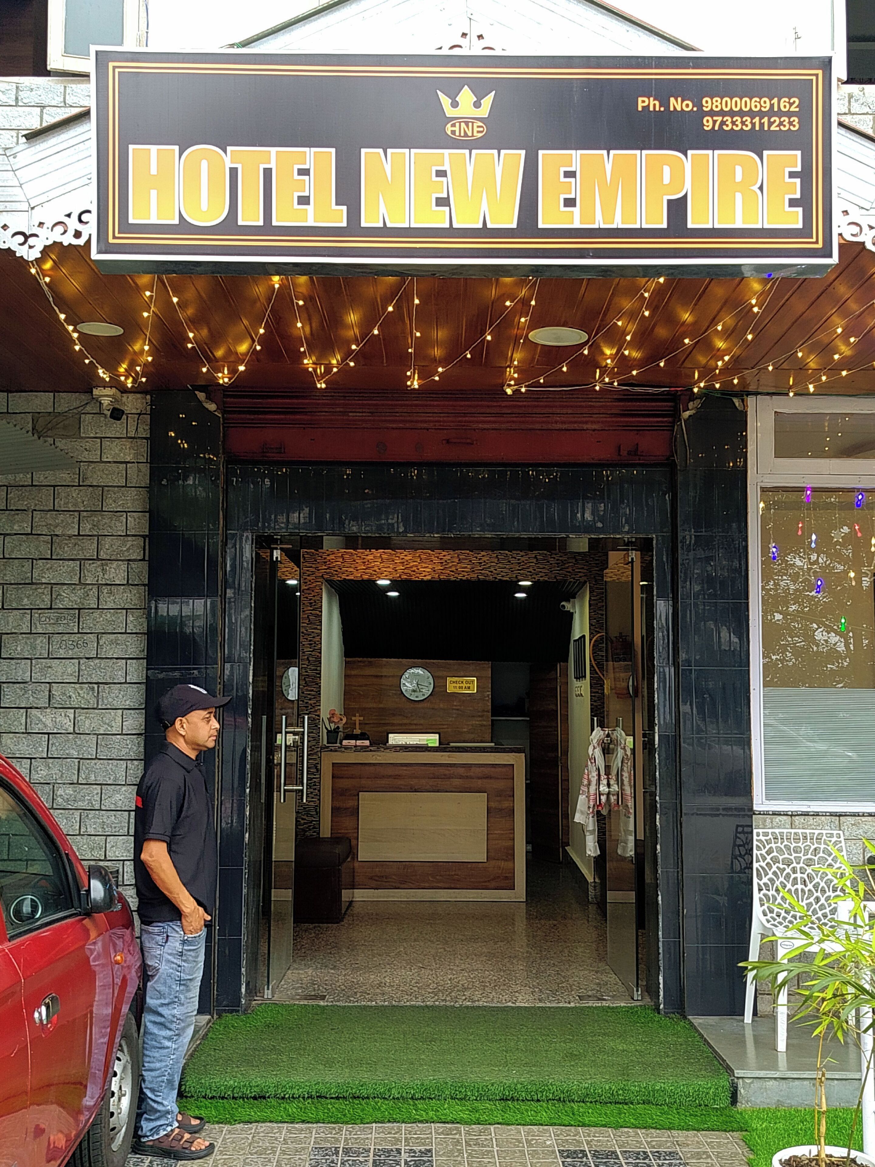 A hotel entrance with a reception desk, a clock, and a sign above stating 'HOTEL NEW EMPIRE.'