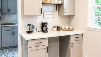 A kitchen with a built-in coffee bar, cabinets, and a window.