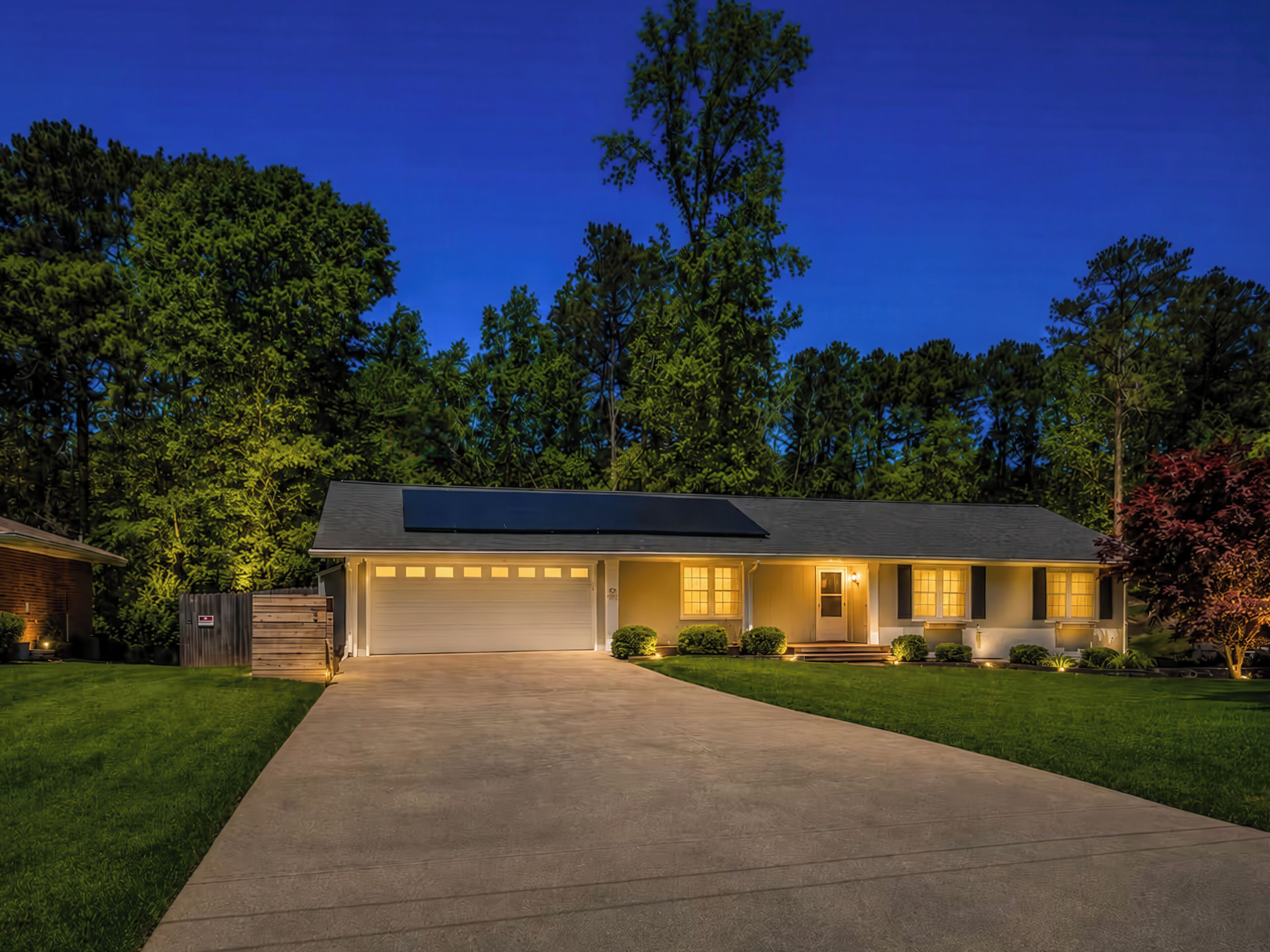 A single-story house with a garage, solar panels, and a well-maintained lawn.