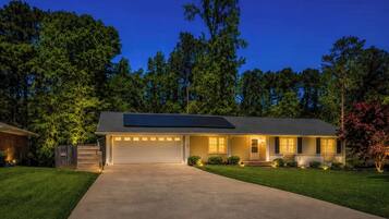 A single-story house with a garage, solar panels, and a well-maintained lawn.