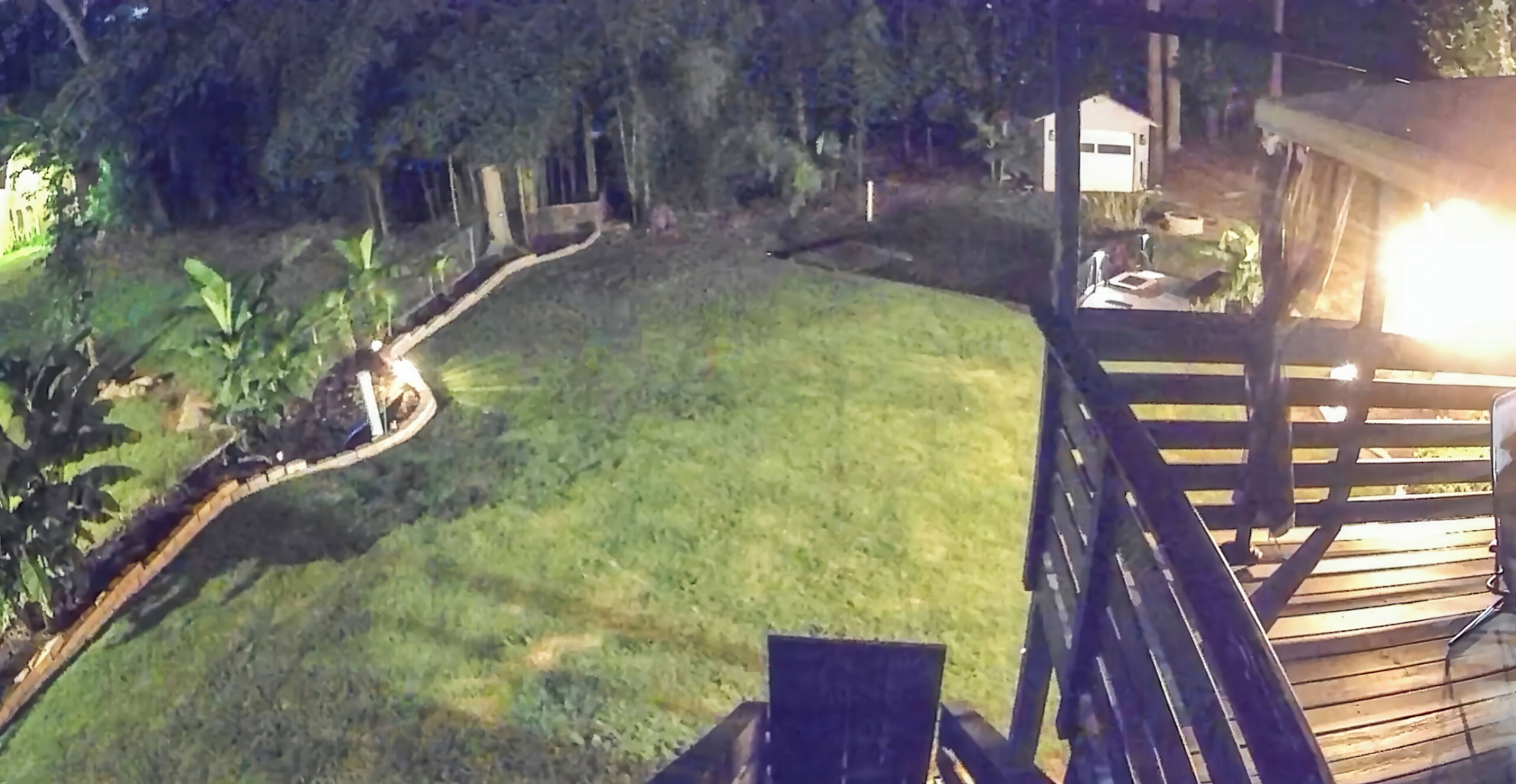 A deck with a view of a grassy yard and a house in the background.