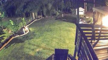 A deck with a view of a grassy yard and a house in the background.