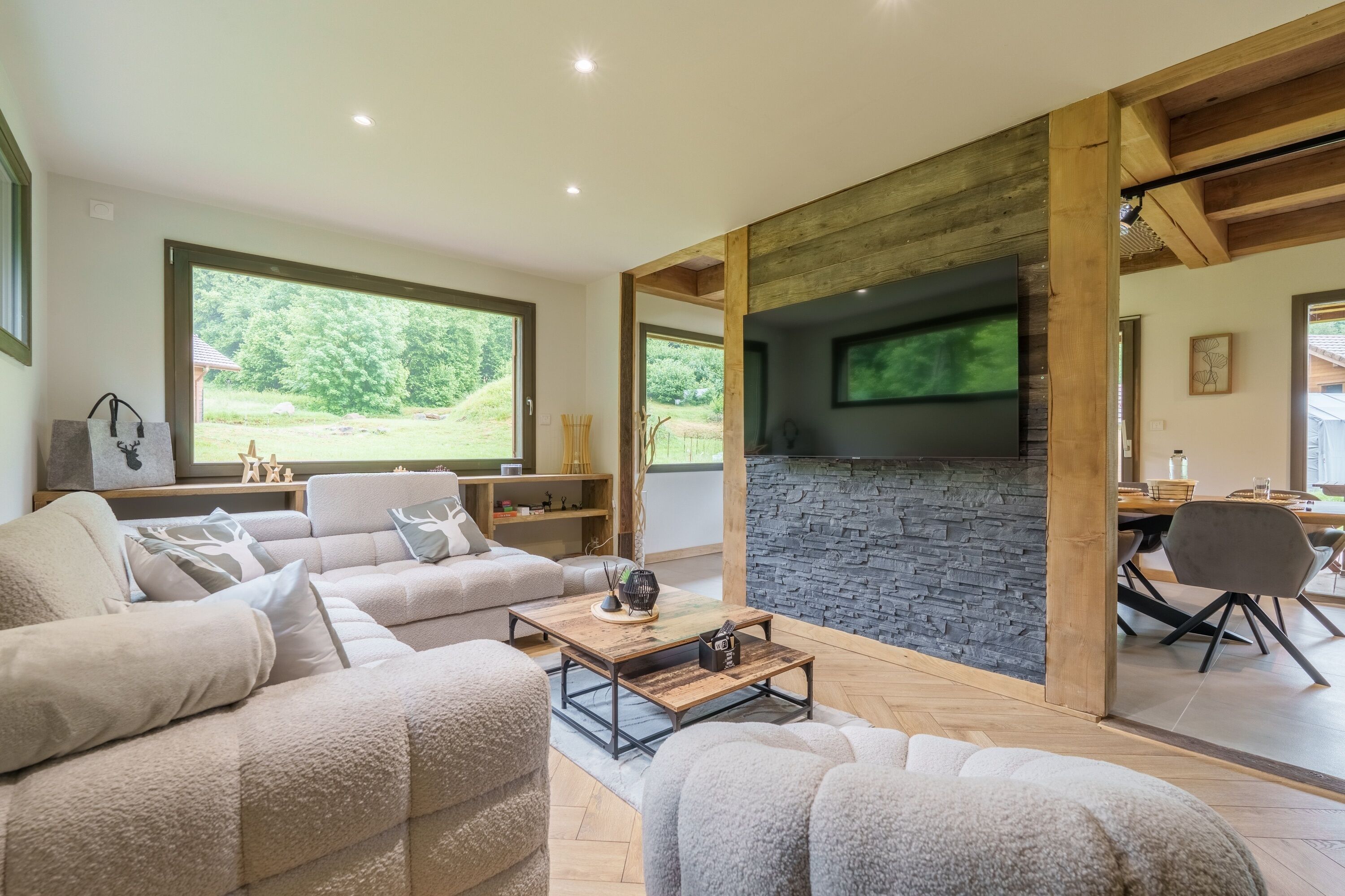 A modern living room with a stone fireplace, large windows, and a cozy seating area.
