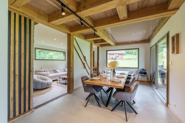 Un intérieur moderne comprenant un coin repas, un ensemble de canapés et une vue sur l’extérieur.