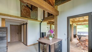 Um interior moderno com teto de madeira, área de jantar com mesa e cadeiras, e vista para um pátio externo através de uma porta de vidro.