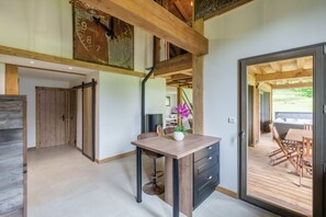 Ein modernes Interieur mit Holzboden, einer Essecke mit Tisch und Stühlen sowie einem Blick durch eine Glastür auf eine Terrass'.